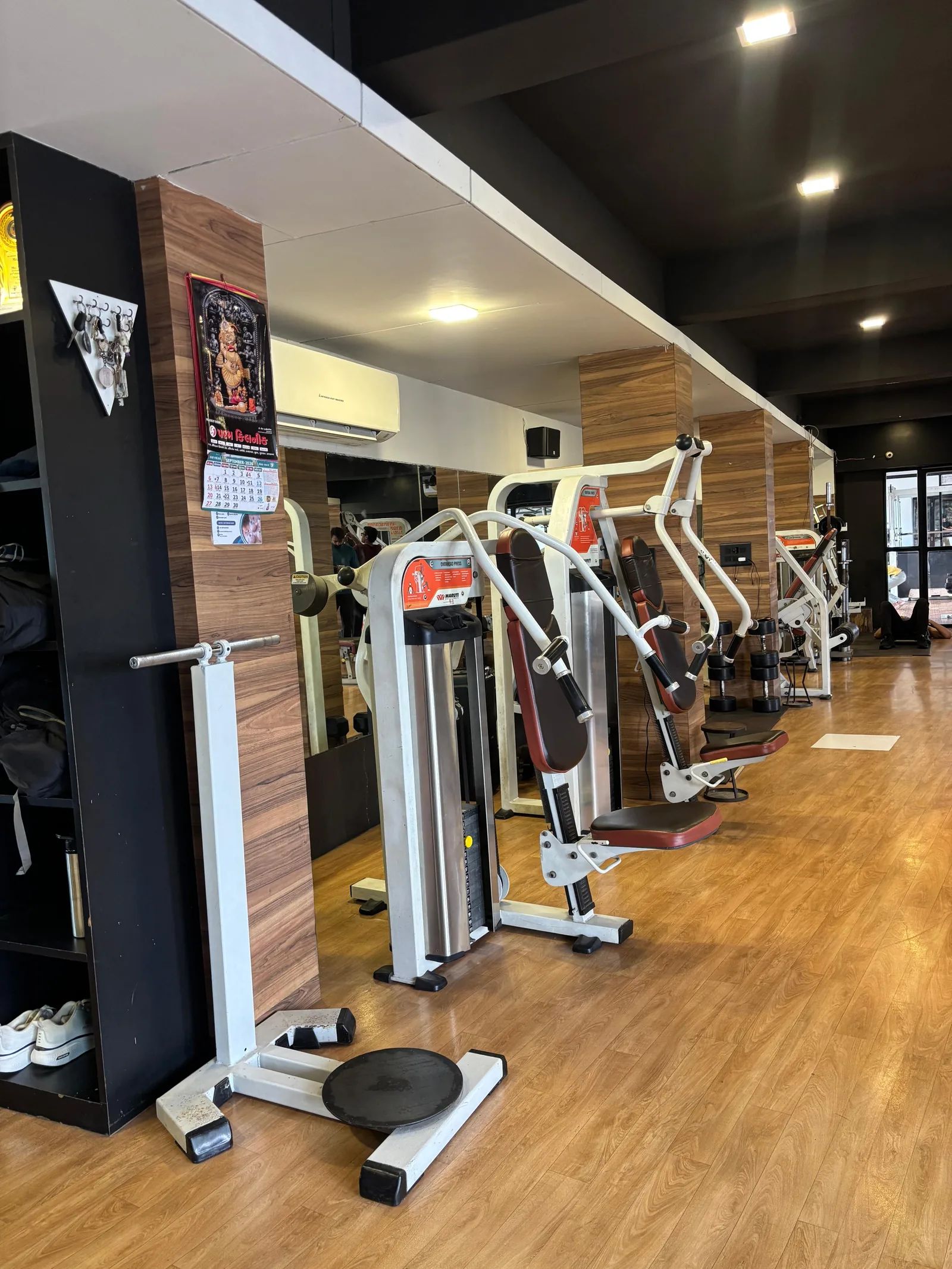 A wider view of the training floor at S R Gym Adajan showing machines and open floor space