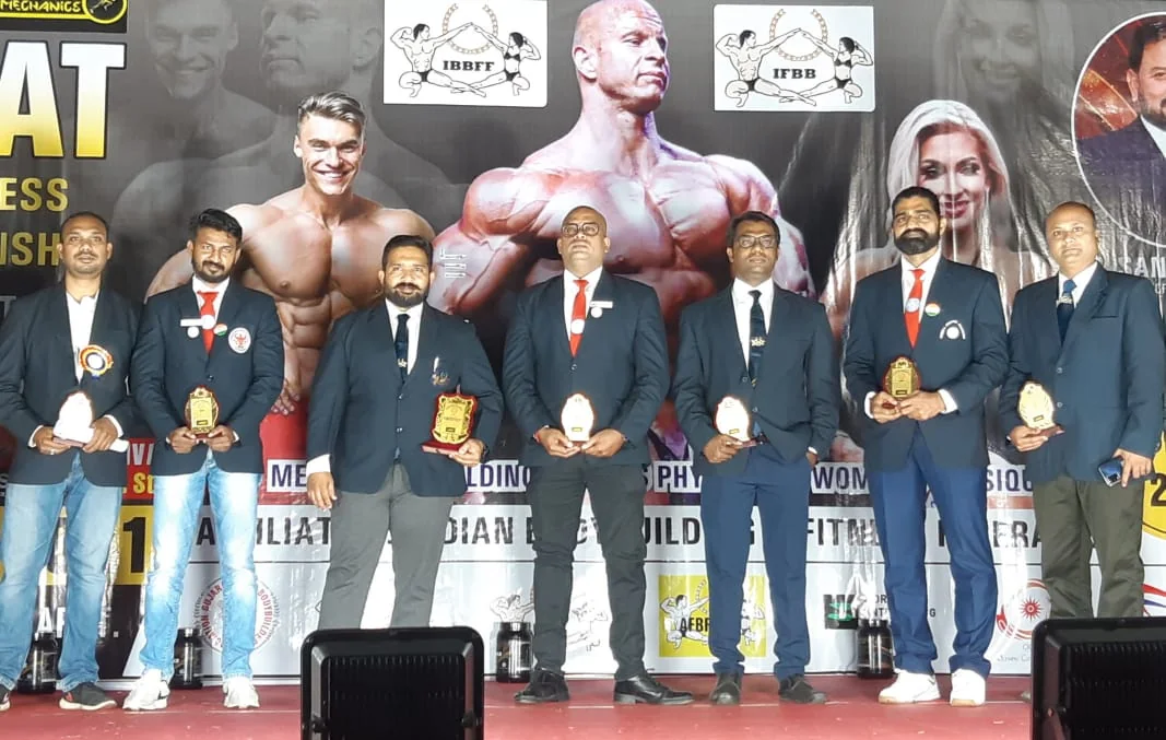 Brijesh Joshi with fellow officials on stage at an IBBFF bodybuilding championship